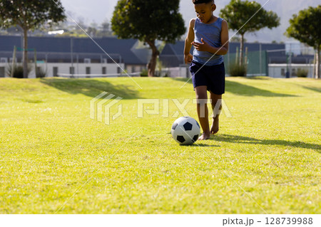 African American boy running on grassy field in neighborhood, dribbling soccer ball, copy space African American boy running on grassy field in neighborhood, dribbling soccer ball, copy space 128739988