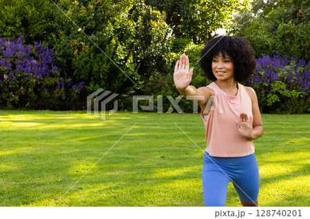 Woman practicing martial arts on lush garden lawn in sunny park, focusing on balance, copy space Woman practicing martial arts on lush garden lawn in sunny park, focusing on balance, copy space 128740201