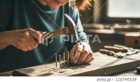 ハンマーで釘を打つクラフト作業の手元 128740539
