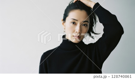 髪をかき上げる黒タートルネックの女性のポートレイト	 128740861