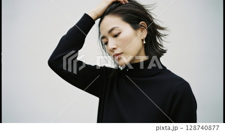 髪をかき上げる黒タートルネックの女性のポートレイト 128740877