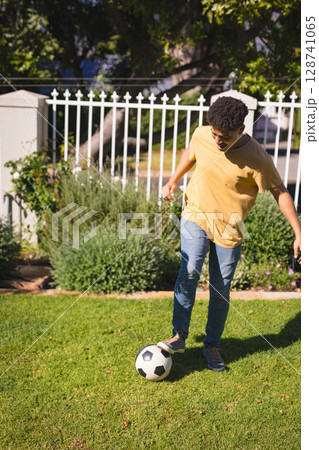 Man balancing black-and-white soccer ball on grassy lawn in residential yard, copy space Man balancing black-and-white soccer ball on grassy lawn in residential yard, copy space 128741065