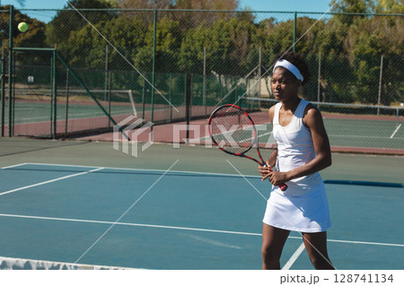 Female tennis player preparing to hit ball on hard court, with racket and ball, copy space Female tennis player preparing to hit ball on hard court, with racket and ball, copy space 128741134