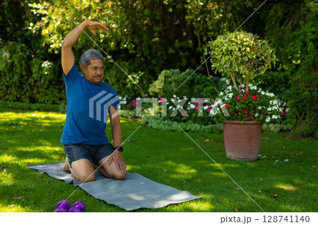 Senior man kneeling, stretching side in backyard, with purple dumbbells terracotta pot, copy space Senior man kneeling, stretching side in backyard, with purple dumbbells terracotta pot, copy space 128741140