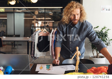 Male fashion designer reviewing sketches and swatches in fashion studio, with laptop, copy space Male fashion designer reviewing sketches and swatches in fashion studio, with laptop, copy space 128741238