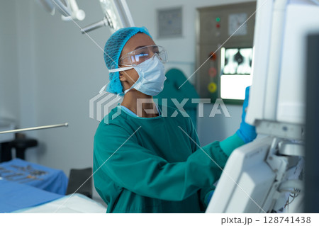 African American woman adjusting imaging monitor in operating room, with instrument tray African American woman adjusting imaging monitor in operating room, with instrument tray 128741438