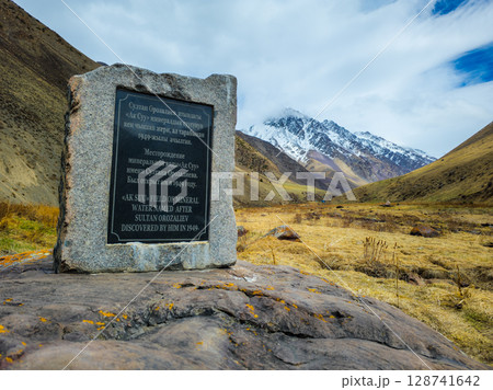 Stone monument Ak-Suu mineral water source at spring day. Stone monument Ak-Suu mineral water source at spring day. 128741642