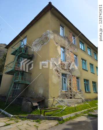 Multi-story building with exterior damage near hillside Multi-story building with exterior damage near hillside 128741651
