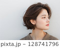 白い壁の前で横を向くショートヘアの若い日本人女性のポートレート 128741796