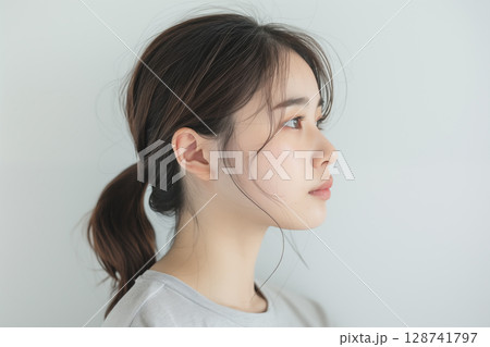 白い背景の前で横を向くポニーテールの日本人女性のナチュラルポートレート 128741797
