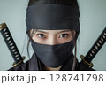 二本の刀を背負い黒装束に身を包んだ若い日本人女性のクローズアップ忍者ポートレート 128741798