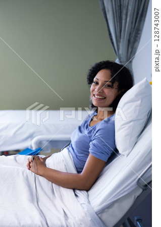 Woman reclining in bed in hospital room, using pillow and blanket, showing IV line, copy space Woman reclining in bed in hospital room, using pillow and blanket, showing IV line, copy space 128743007