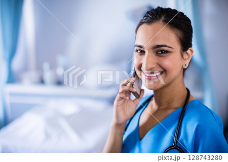 Indian woman smiling talking on smartphone and holding stethoscope in hospital room, copy space Indian woman smiling talking on smartphone and holding stethoscope in hospital room, copy space 128743280