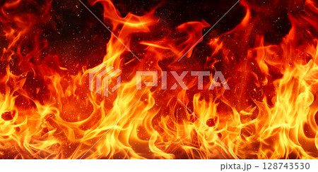 火花を散らしながら燃える炎の背景素材。黒背景で燃えるリアルな炎。炎のエネルギッシュな躍動と爆ぜる火花 128743530