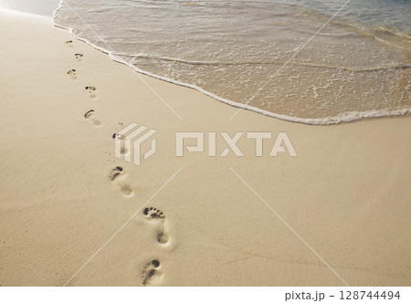 Footprints on empty sandy beach 128744494