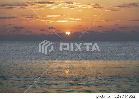 Sun rising over calm ocean Sun rising over calm ocean 128744952