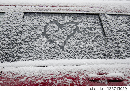 Heart shape drawn on snow covered car window 128745039