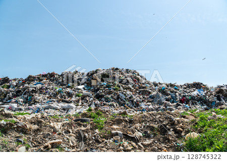 A massive pile of waste sits in a landfill under a blue sky, raising concerns about the environment and waste management 128745322