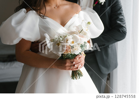 Bride And Groom Embracing With Bouquet 128745558