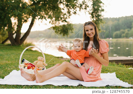 Mother And Baby Enjoying Lake Picnic Mother And Baby Enjoying Lake Picnic 128745570