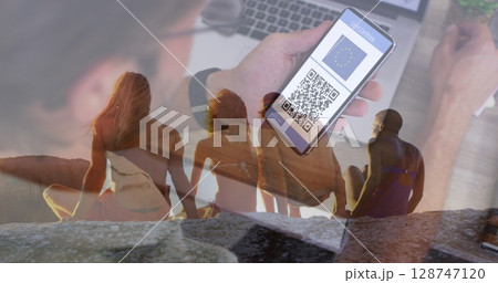 Image of man with covid passport on smartphone over back view of diverse friends on beach 128747120
