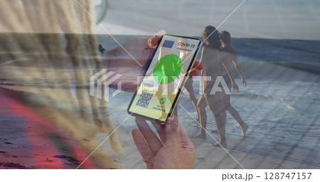 Image of caucasian woman with smartphone over caucasian women at beach 128747157