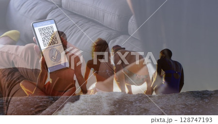 Image of diverse friends at beach over caucasian woman with smartphone 128747193