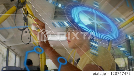 Gripping strap male in yellow tee reaching overhead on city bus, with holographic data display 128747472