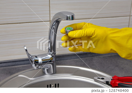 changing the faucet aerator in a mettallic kitchen sink changing the faucet aerator in a mettallic kitchen sink 128748400
