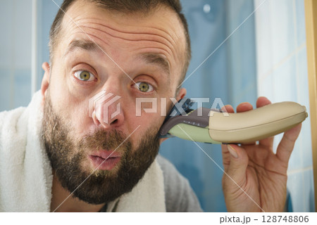 Man shaving trimming his beard Man shaving trimming his beard 128748806