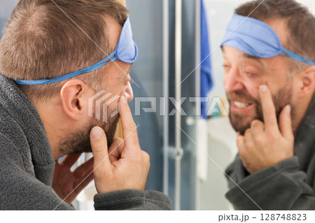 Sleepy man looking at mirror Sleepy man looking at mirror 128748823
