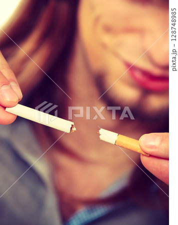 Young man is breaking a cigarette Young man is breaking a cigarette 128748985