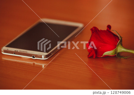 Smartphone and single red rose. Smartphone and single red rose. 128749006