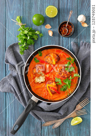 fish cakes in tomato vegetable coconut milk sauce 128749081