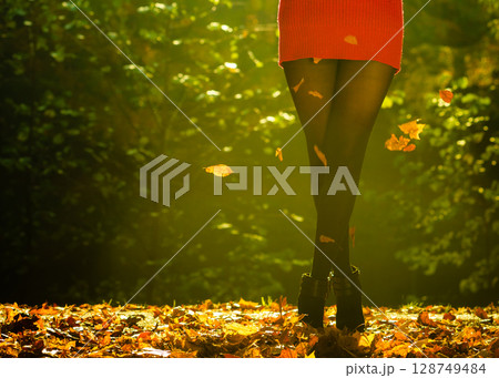 Joyful girl having fun with leaves in autumnal park. 128749484