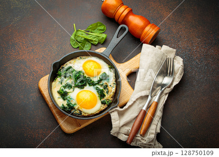 Healthy spinach omelette in cast iron pan for breakfast top view Healthy spinach omelette in cast iron pan for breakfast top view 128750109