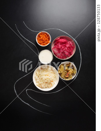 Probiotic foods for gut health inside stomach outline drawn on black chalk board top view 128750133