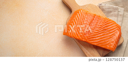 Fresh salmon fillet on cutting board, delicious and healthy meal preparation top view, space for text Fresh salmon fillet on cutting board, delicious and healthy meal preparation top view, space for text 128750137