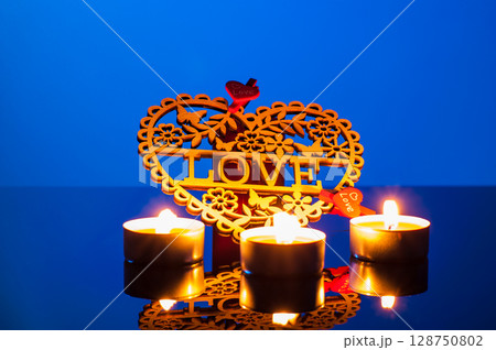 Bright candles burn on a deep blue background, creating an atmosphere of peace and tenderness 128750802