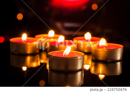 Flickering candles dance in the dark, pushing back the gloom 128750876