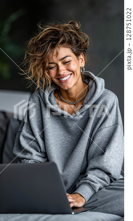 A woman sitting on a couch using a laptop computer 128751022