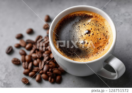 A cup of coffee and coffee beans on a table 128751572