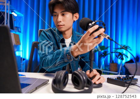 Young man adjusting microphone for podcast recording in home studio Young man adjusting microphone for podcast recording in home studio 128752543