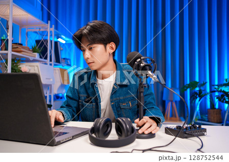 Young man working on podcast production with microphone and laptop in studio Young man working on podcast production with microphone and laptop in studio 128752544