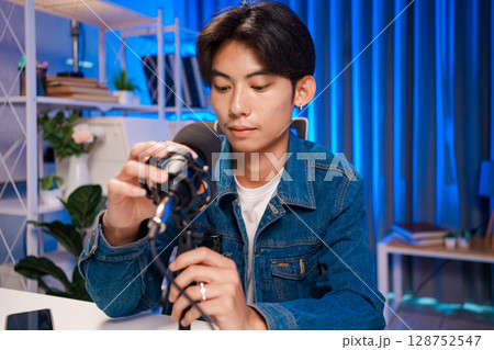 Young man adjusting microphone for podcast recording in home studio 128752547