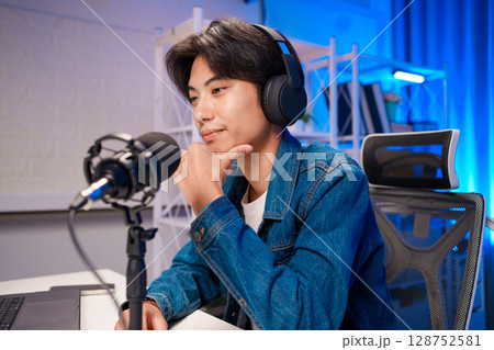 Asian podcaster looking relaxed during show Asian podcaster looking relaxed during show 128752581