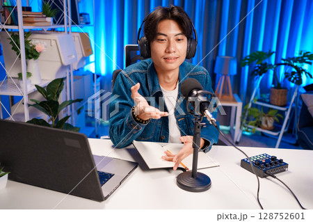 Smiling man podcaster make audio podcast with headphones and microphone in modern home studio. 128752601