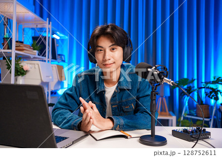 Smiling man podcaster make audio podcast with headphones and microphone in modern home studio. 128752611