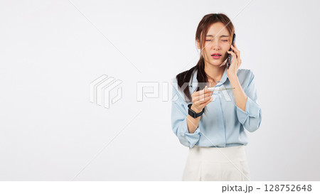 Feeling sick, a woman worried about temperature talks on phone, possibly calling a doctor about her disease as she holds a thermometer, and knows she is really sick, isolated studio white background Feeling sick, a woman worried about temperature talks on phone, possibly calling a doctor about her disease as she holds a thermometer, and knows she is really sick, isolated studio white background 128752648