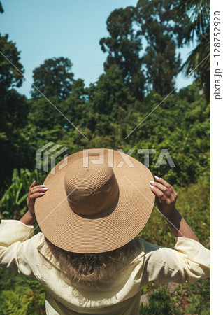 Woman in Straw Hat Admiring Tropical Forest View 128752920